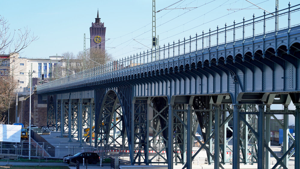 Im Vordergrund das blau gestrichene Bahnviadukt, im Hintergrund der dunkelrote Uhrenturm des Wirkbaus.