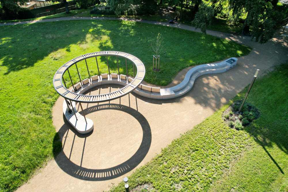 Große Holz-Pergola mit langer Sitzbank im grünen Park, aus der Vogelperspektive fotografiert.