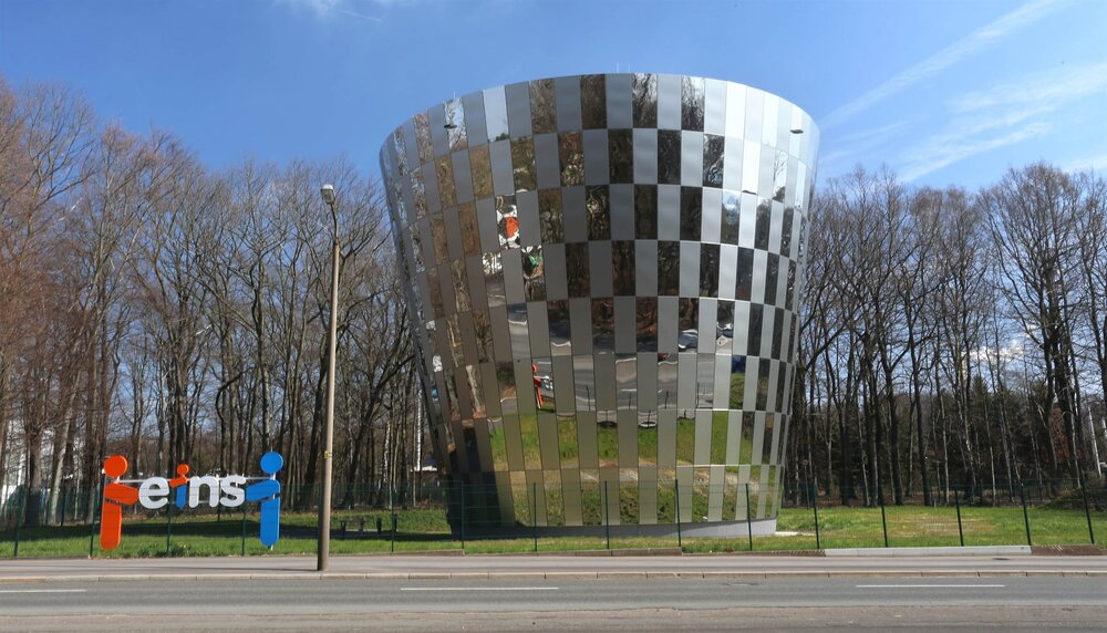 Mittig ist der kegelförmige Trinkwasserspeicher mit Edelstahlmantel zu sehen. Am linken Bildrand befindet sich ein Aufsteller mit dem Logo von eins energie in sachsen.