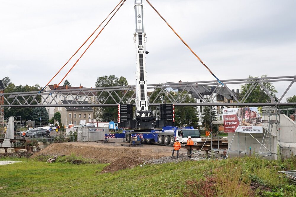 Der 65 Tonnen schwere Stahloberbau der Brücke im Pleißenbachgrünzug wurde mit einem 650 Tonnen schweren Autokran in die vorbereiteten Widerlager eingehoben.