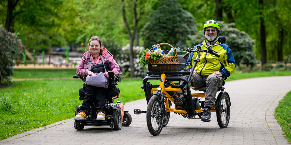 Rollstuhlfahrende und ein Paralleltandemfahrender auf dem Weg durch den Schloßteichpark
