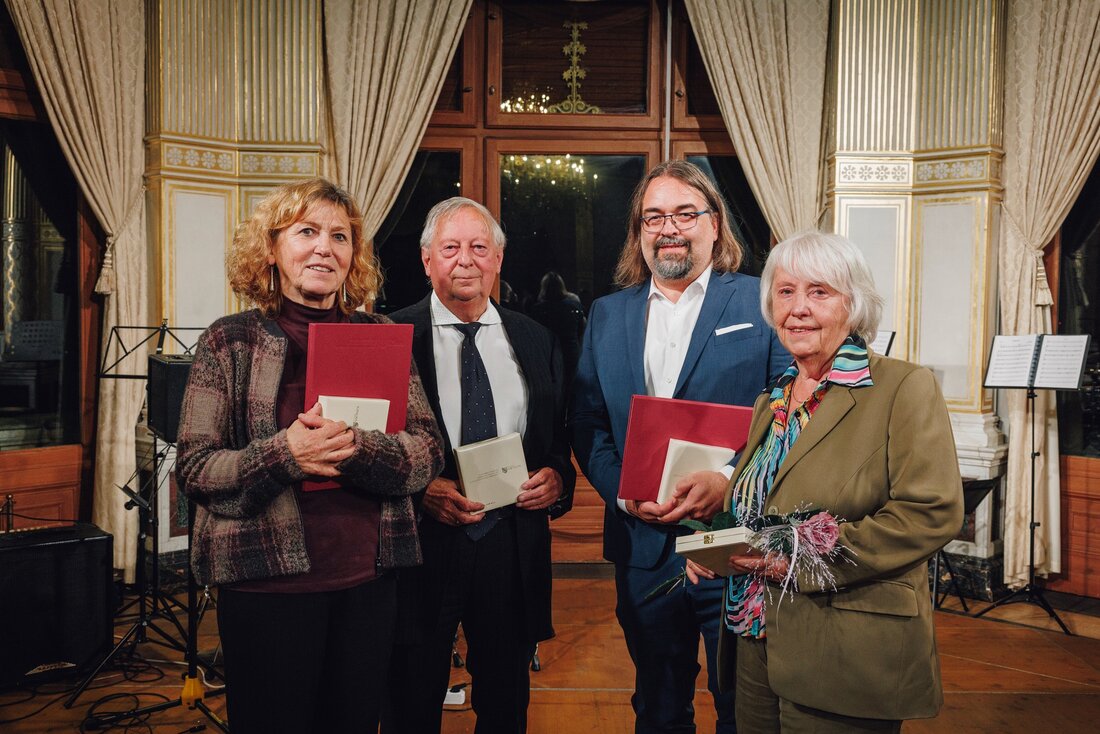 Die Preisträger stehen mit Urkunde und Medaille in festlichem Saal.