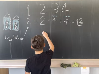 Kind der gruuna Schule rechnet den Verbrauch an Milchkartons aus