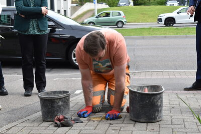 Ein Bauarbeiter verlegt die Stolpersteine in den Boden.