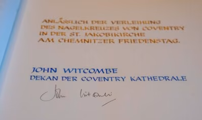 Das Bild zeigt den Eintrag in das Goldene Buch der Stadt Chemnitz von The Very Reverend Dean John Witcombe, Vorsteher der Coventry Gemeinde. Der Text lautet "Anlässlich der Verleihung des Nagelkreuzes von Coventry in der St. Jakobikirche am Chemnitzer Friedenstag".