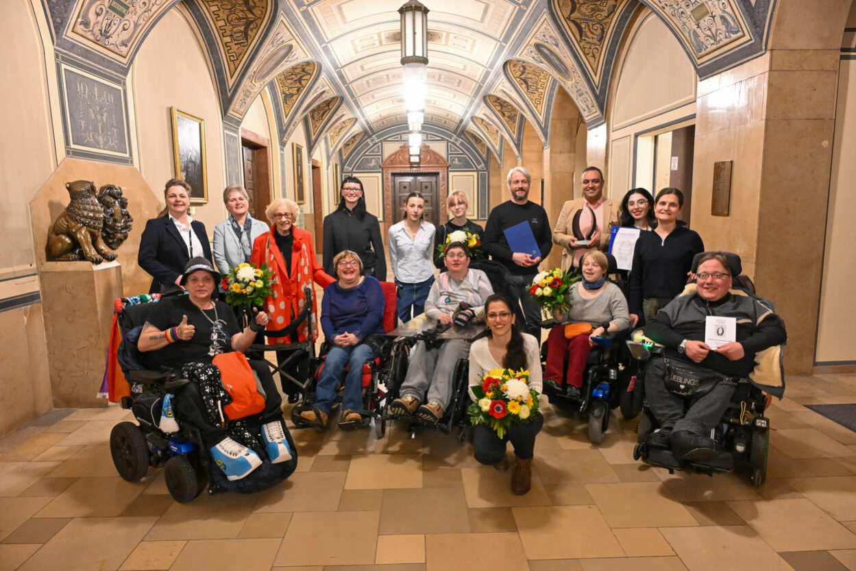 Das Bild zeigt eine Gruppe von Menschen in der Wandelhalle des Chemnitzer Rathauses. Die Menschen schauen in die Kamera, manche von ihnen tragen Urkunden in den Händen