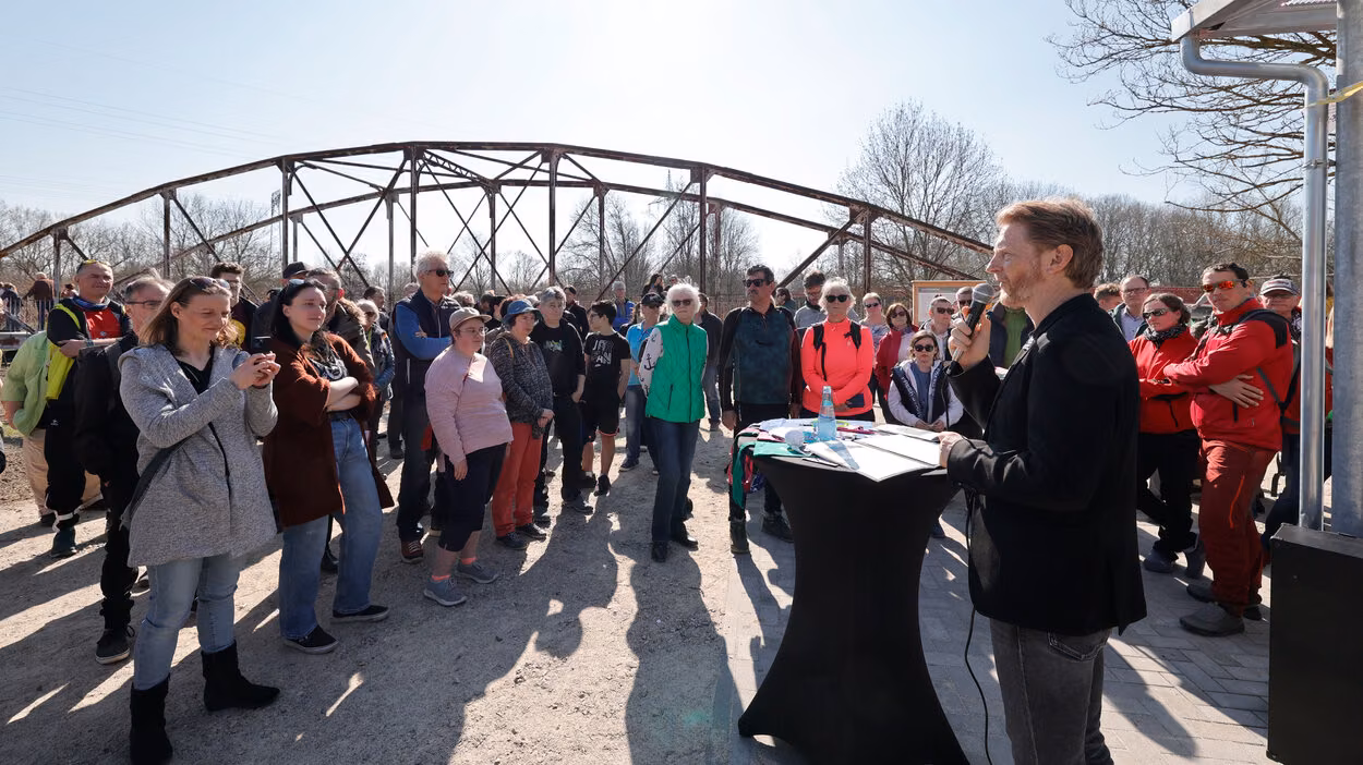Baubürgermeister Michael Stötzer bei der Einweihung vor historischer Brücke, Zuhörer im Hintergrund.