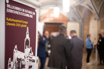 Welcome poster for the residents' meeting with people in the background