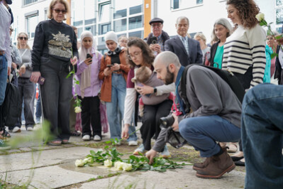 Angehörige legen Rosen am Stolperstein nieder.