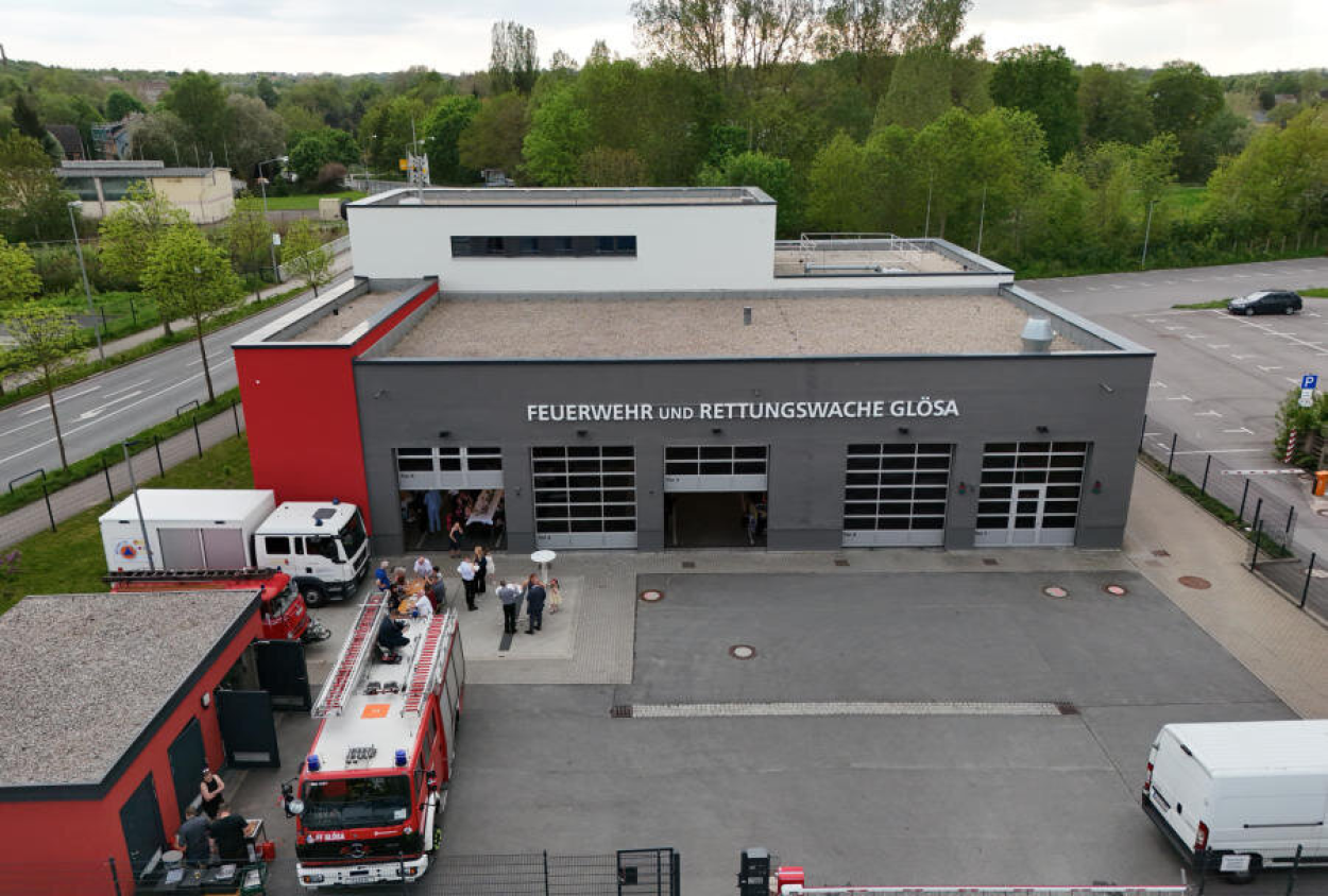Das Gerätehaus der Freiwilligen Feuerwehr ist dunkelgrau und hat fünf Einfahrten für Feuerwehrfahrzeuge. Im Vordergrund auf der linken Seite ist ein rotes Nebengebäude zu sehen.