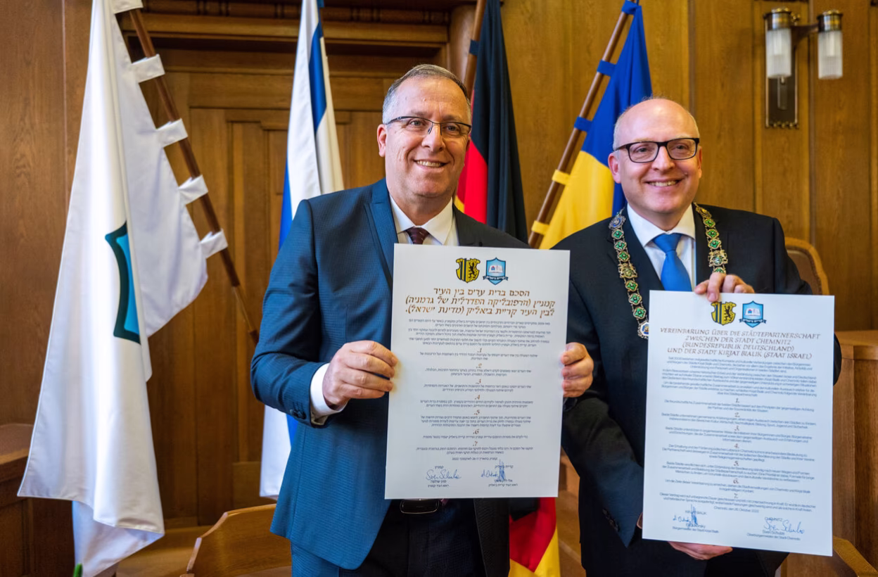 Die beiden (Ober)Bürgermeister halten die unterschriebene Vereinbarung in deutsch und hibräisch in den Händen.