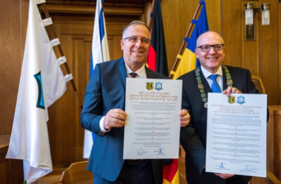 Die beiden (Ober)Bürgermeister halten die unterschriebene Vereinbarung in deutsch und hibräisch in den Händen.