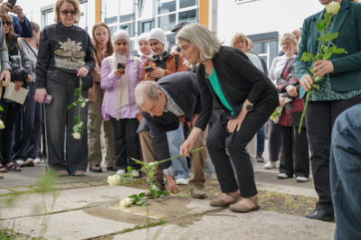 Angehörige legen Rosen am Stolperstein nieder.