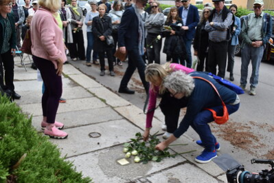 Angehörige legen Rosen am Stolperstein nieder.