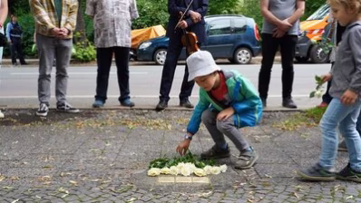 Teilnehmende der Stolpersteinverlegung legen Blumen nieder