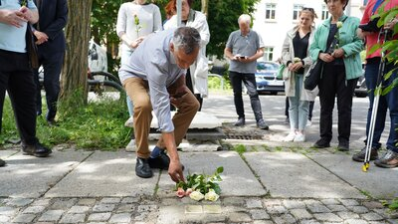 Teilnehmende der Stolpersteinverlegung legen Blumen nieder