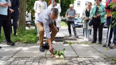 Teilnehmende der Stolpersteinverlegung legen Blumen nieder