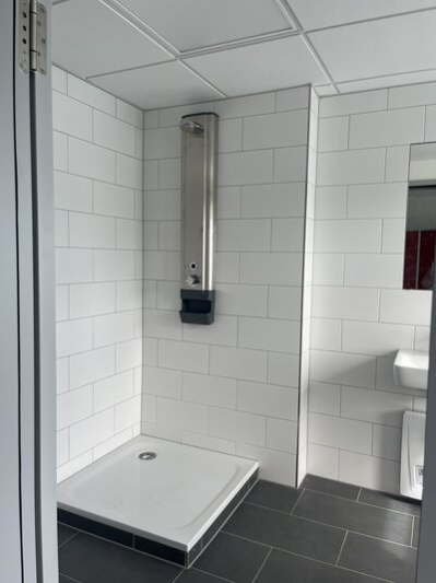 Das Bild zeigt einen Raum mit einer Dusche im Bestandsgebäude für die Badaufsicht.