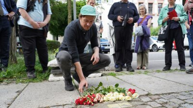 Teilnehmende der Stolpersteinverlegung legen Blumen nieder