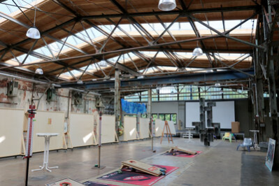 Großer Veranstaltungssaal in alter Fabrikhalle mit hölzerner Decke und Oberlichtern.