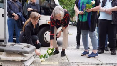 Teilnehmende der Stolpersteinverlegung legen Blumen nieder