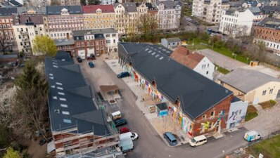 Das Drohnenbild zeigt die Stadtwirtschaft von oben. Zu sehen sind die bunten Malereien an dem Gebäude.