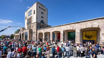 Besucherinnen und Besucher stehen vor den Sportarkaden und dem Marathonturm im Sportforum Chemnitz, Teil des Walk of Fame des Sports.