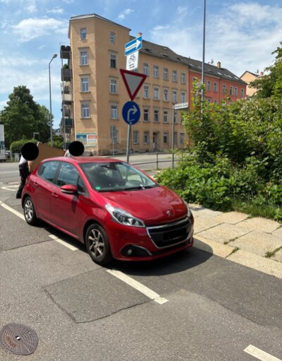 Ein rotes Auto steht auf dem Fahrradstreifen.