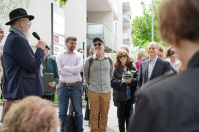 Besucherinnen und Besucher der Stolpersteinverlegung lächeln Dr. Nitsche während seiner Rede freundlich an.
