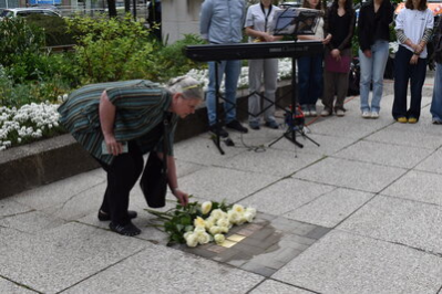Angehörige legen Rosen am Stolperstein nieder.