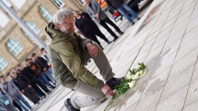 Teilnehmende an der Stolpersteinverlegung legen Blumen nieder
