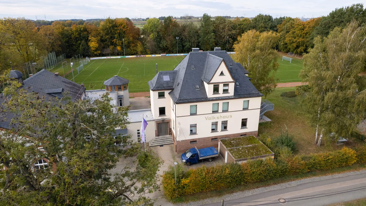 Luftaufnahme des Volkshauses Röhrsdorf mit dem dahinterliegenden Sportplatz.