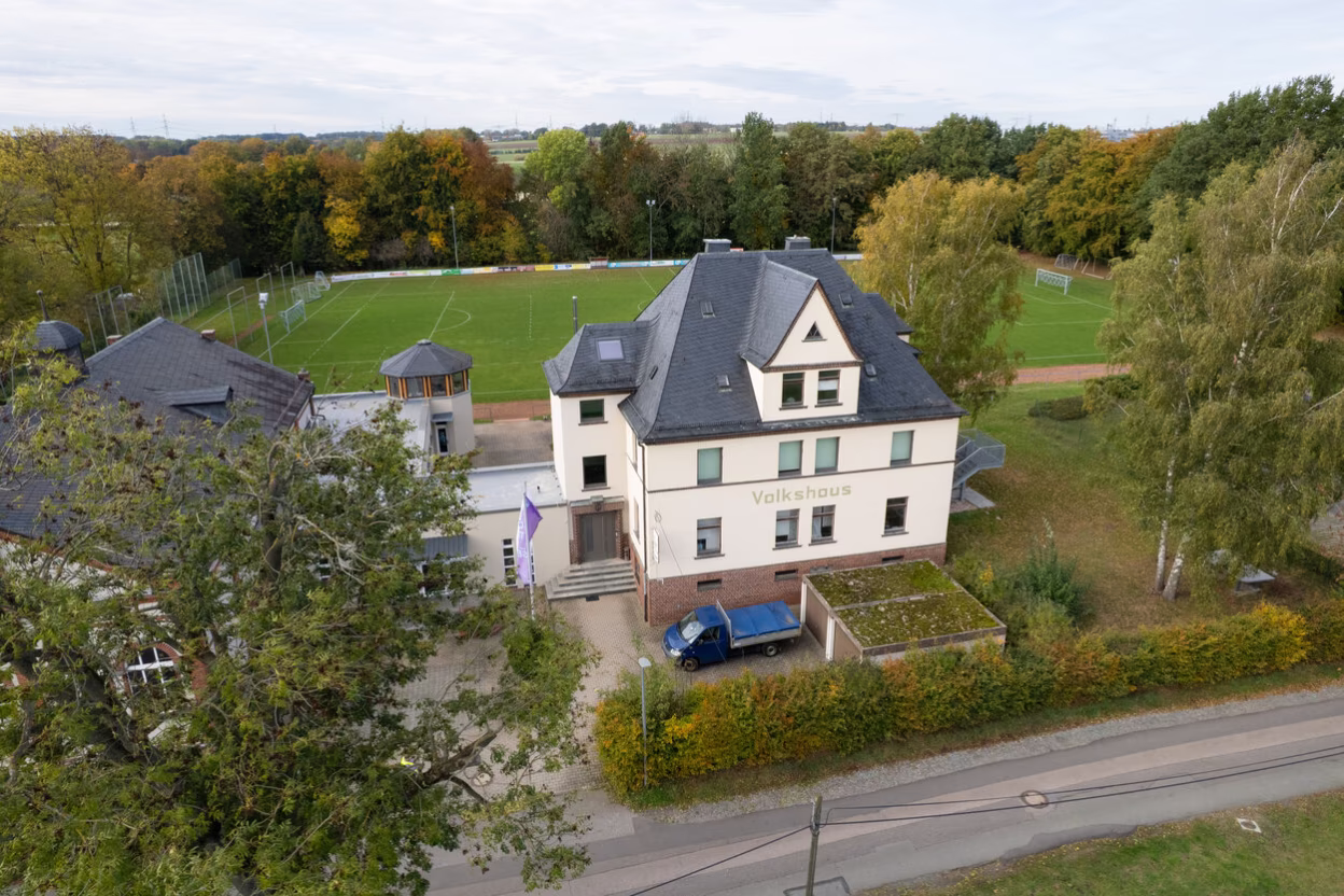 Luftaufnahme des Volkshauses Röhrsdorf mit dem dahinterliegenden Sportplatz.
