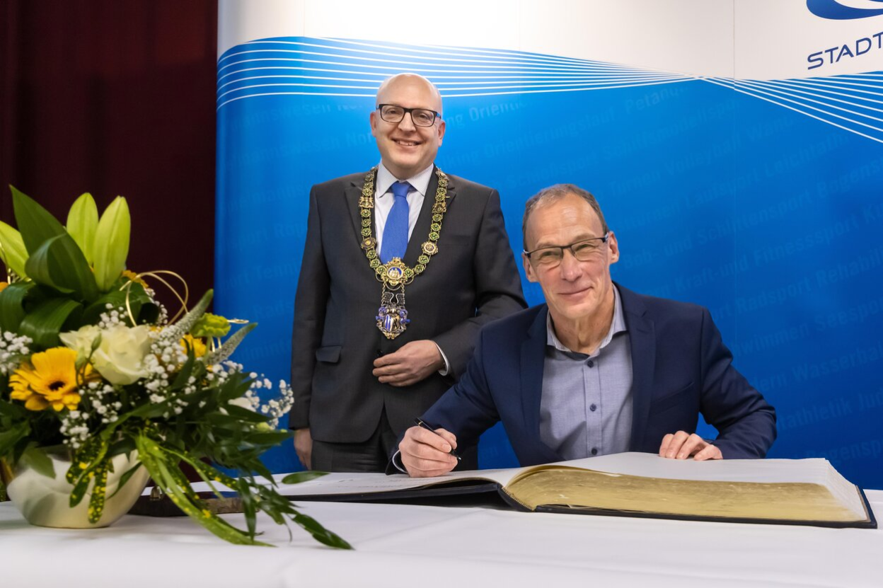 Heiko Schinkitz (vorn) trägt sich im Beisein von Oberbürgermeister Sven Schulze ins Goldene Buch der Stadt ein.
