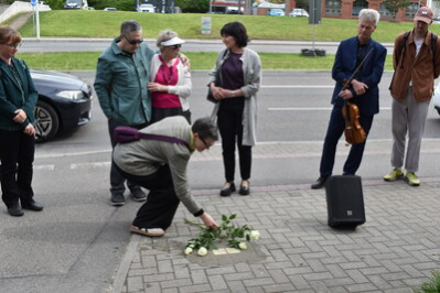 Angehörige legen Rosen am Stolperstein nieder.