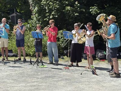 Nine-member trombone choir with musicians of different age groups performing.
