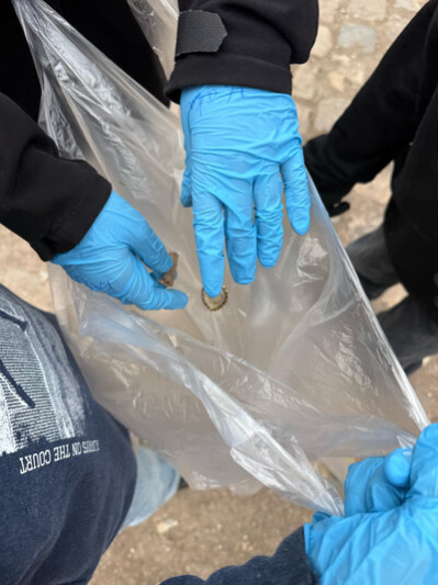 Kinder werfen gefunden Müll in einen Beutel