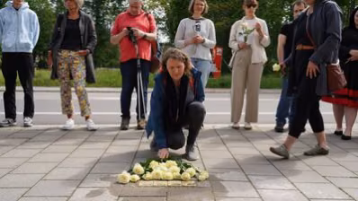 Teilnehmende der Stolpersteinverlegung legen Rosen nieder