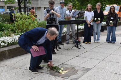 Michael Lachmann legt Rosen am Stolperstein nieder.