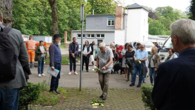 Die Teilnehmenden an der Stolpersteinverlegung für Willy Lesser legen Rosen nieder