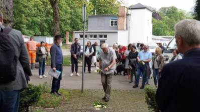 Die Teilnehmenden an der Stolpersteinverlegung für Willy Lesser legen Rosen nieder