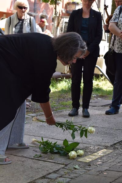 Patin, Ulrike Riethmüller, legt eine Rose neben die Stolperteine.