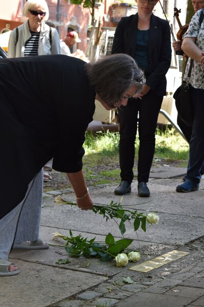 Patin, Ulrike Riethmüller, legt eine Rose neben die Stolperteine.