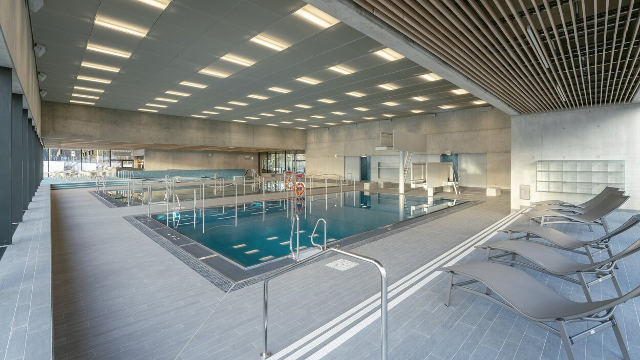 Freizeithalle in der Schwimmhalle Bernsdorfer Bad: Im Vordergrund befinden sich sechs Liegen, dahinter an der Wand Fächer zur Aufbewahrung. In der Mitte des Bildes ist das Sprungbecken zu sehen, im Hintergrund das Lehrschwimmbecken und der Kleinkindbereich.