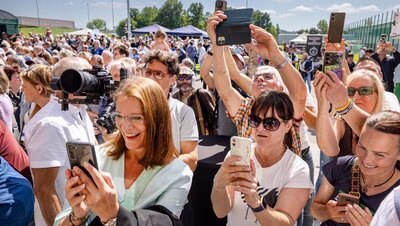 Besucherinnen und Besucher im Sportforum Chemnitz, die Fotos mit ihren Handys machen.