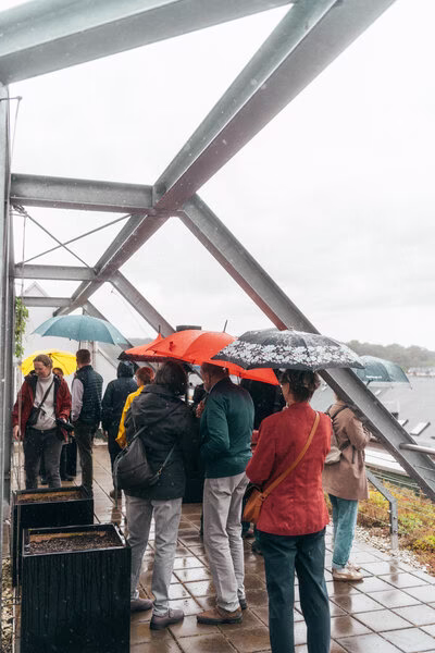 Dachgarten mit Stahlkonstruktion, darunter Besucher mit Regenschirmen in Chemnitz.