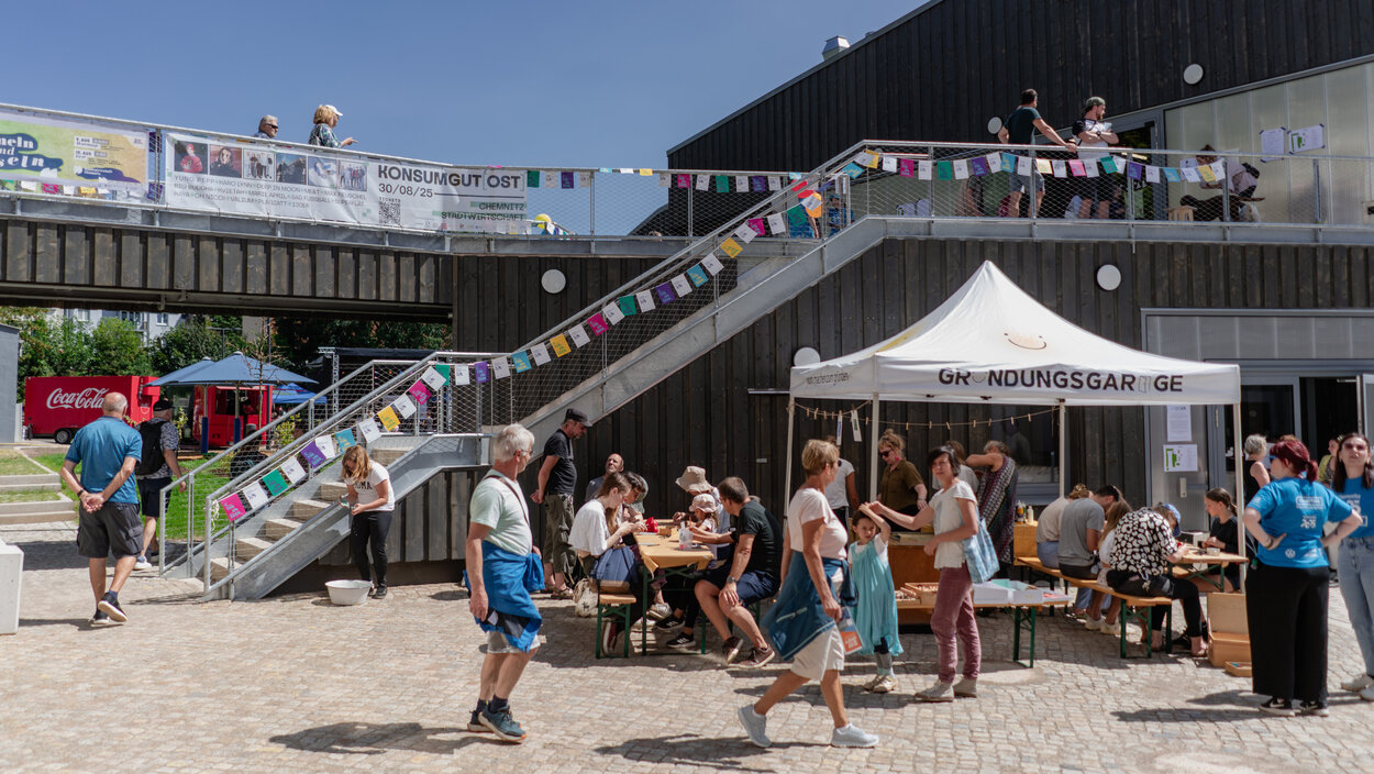 Hof der Stadtwirtschaft Chemnitz mit Treppenaufgang zum ersten Geschoss, Wimpelkette und vielen Menschen beim Hoffest 2025.