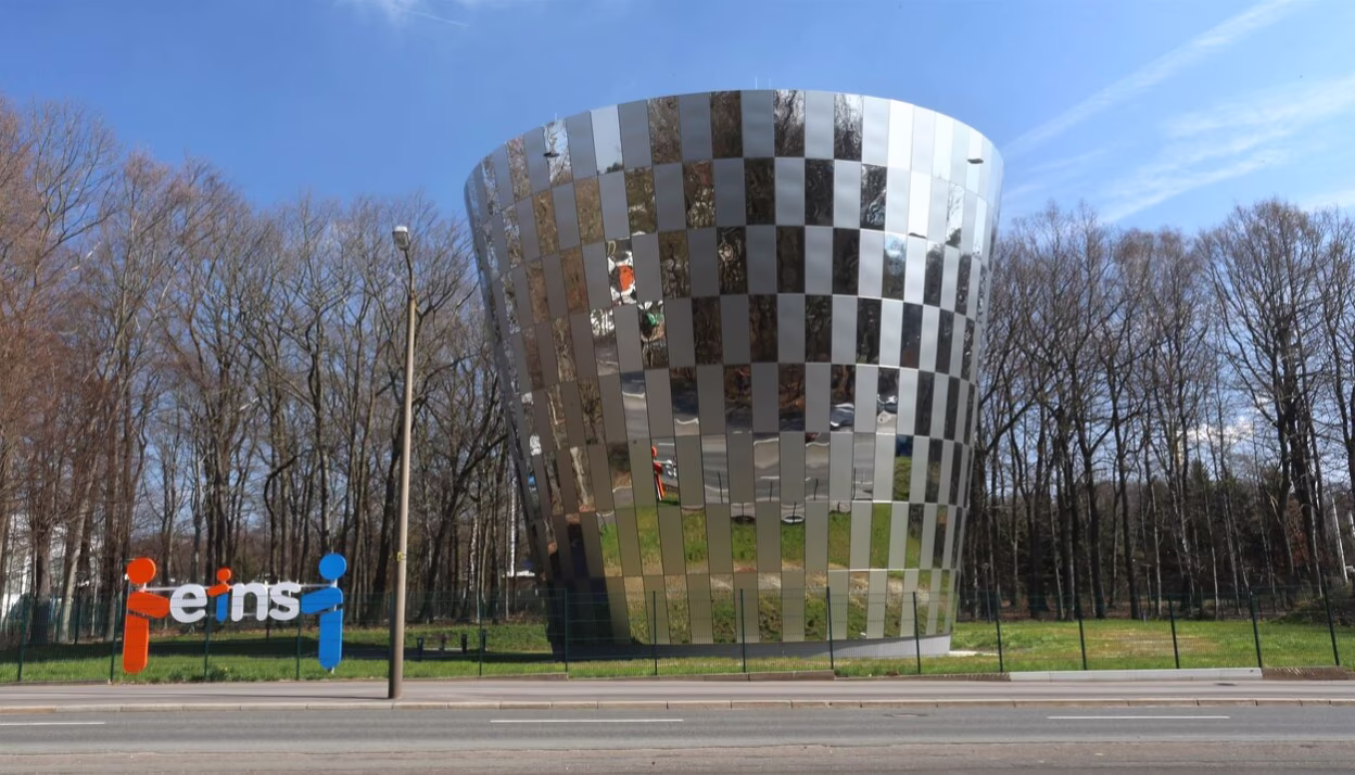 Mittig ist der kegelförmige Trinkwasserspeicher mit Edelstahlmantel zu sehen. Am linken Bildrand befindet sich ein Aufsteller mit dem Logo von eins energie in sachsen.