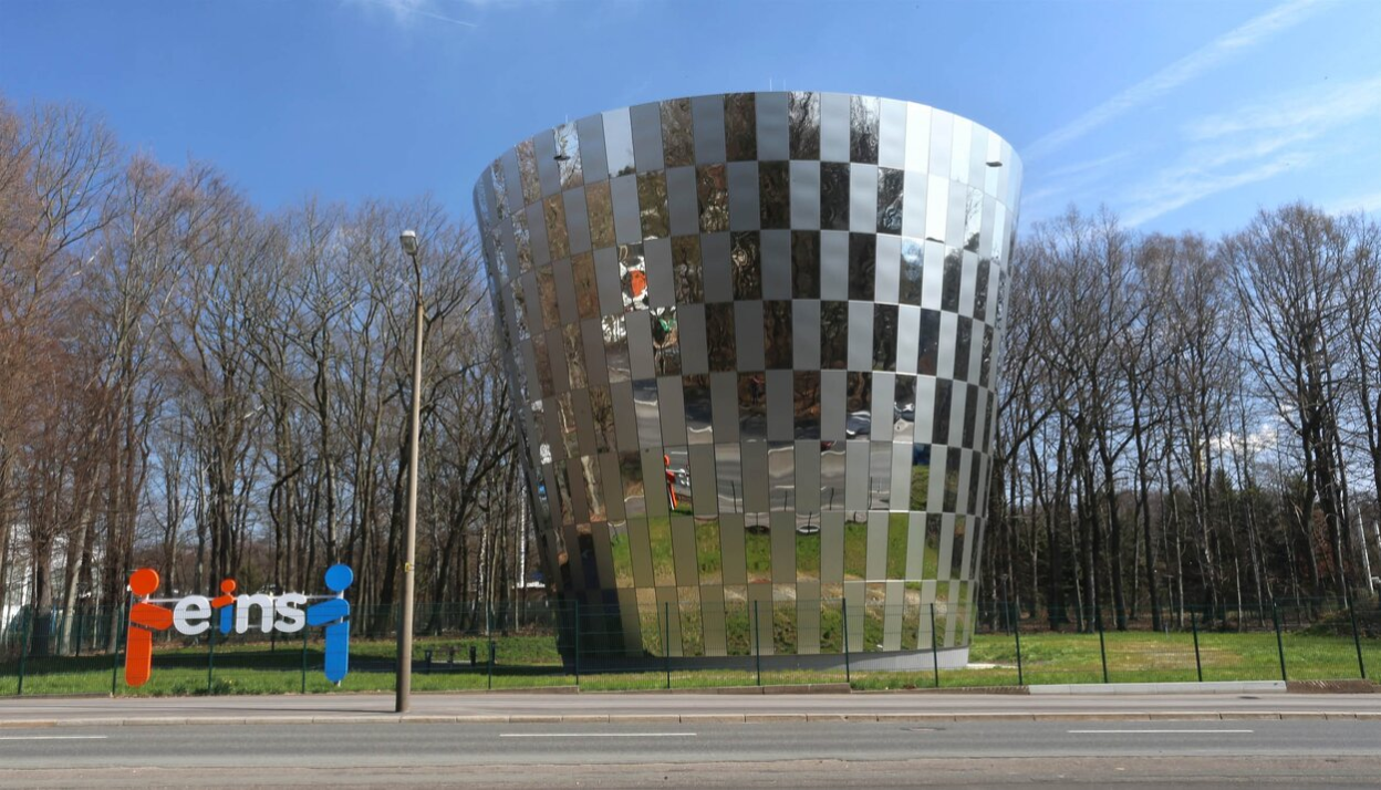 Mittig ist der kegelförmige Trinkwasserspeicher mit Edelstahlmantel zu sehen. Am linken Bildrand befindet sich ein Aufsteller mit dem Logo von eins energie in sachsen.
