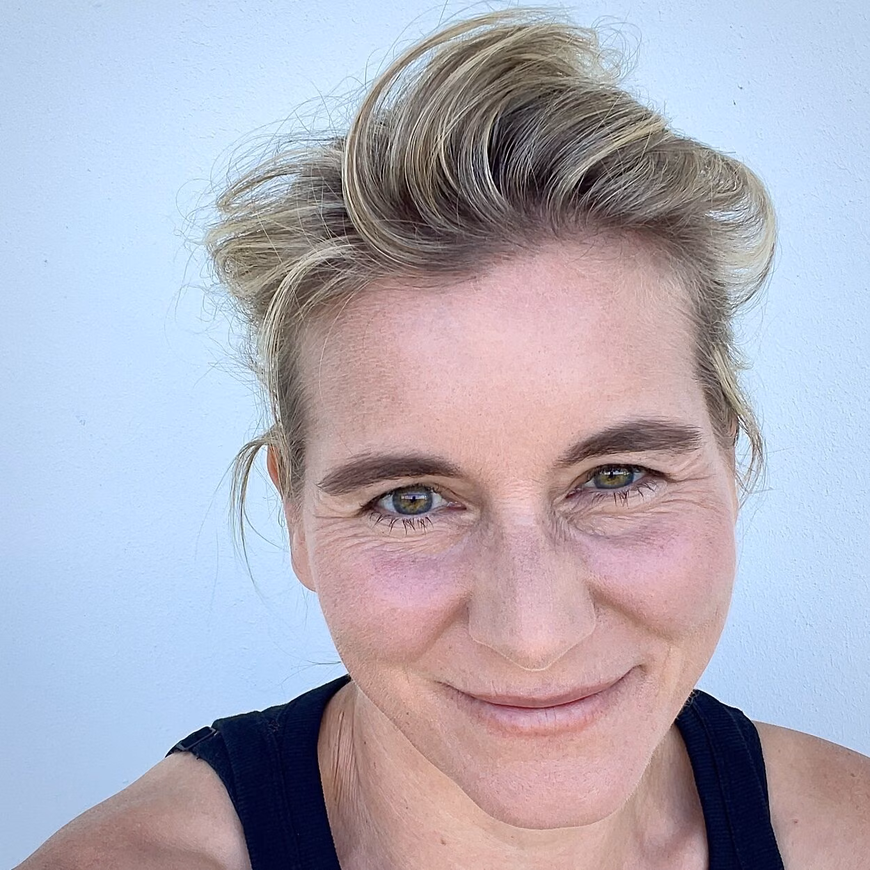 Das Bild zeigt ein Selbstportait von Frauke Angel. Sie schaut direkt in die Kamera. Sie hat ihre blond gestähnten Haare zu einem Zopf zusammengebunden. Sie trägt ein schwarzes Top. Ihre Augenfarbe ist grünbraun. Sie lächelt freundlich in die Kamera.